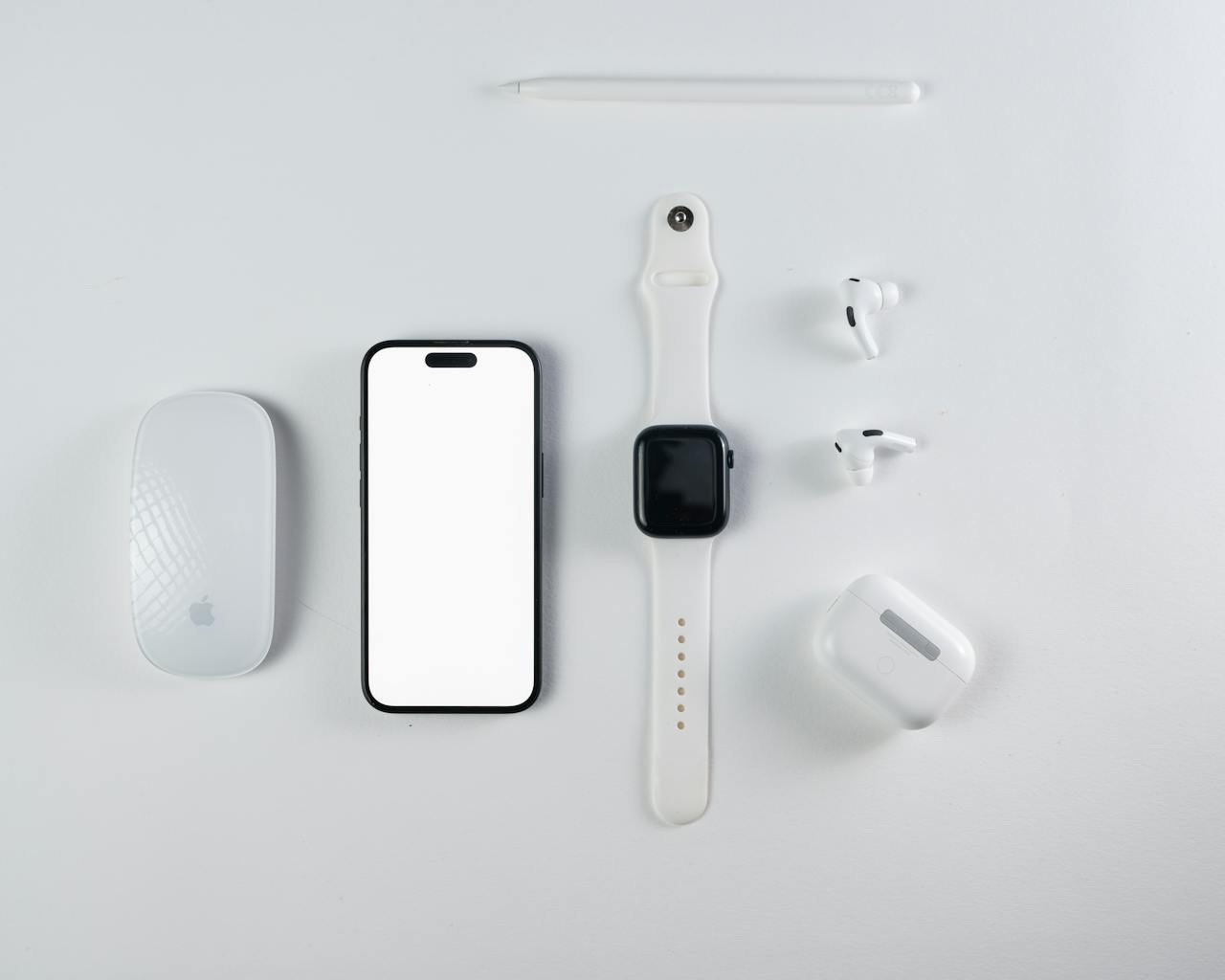 category-02 Minimalist flat lay of smartphone, smartwatch, wireless earbuds, and mouse on a white background.